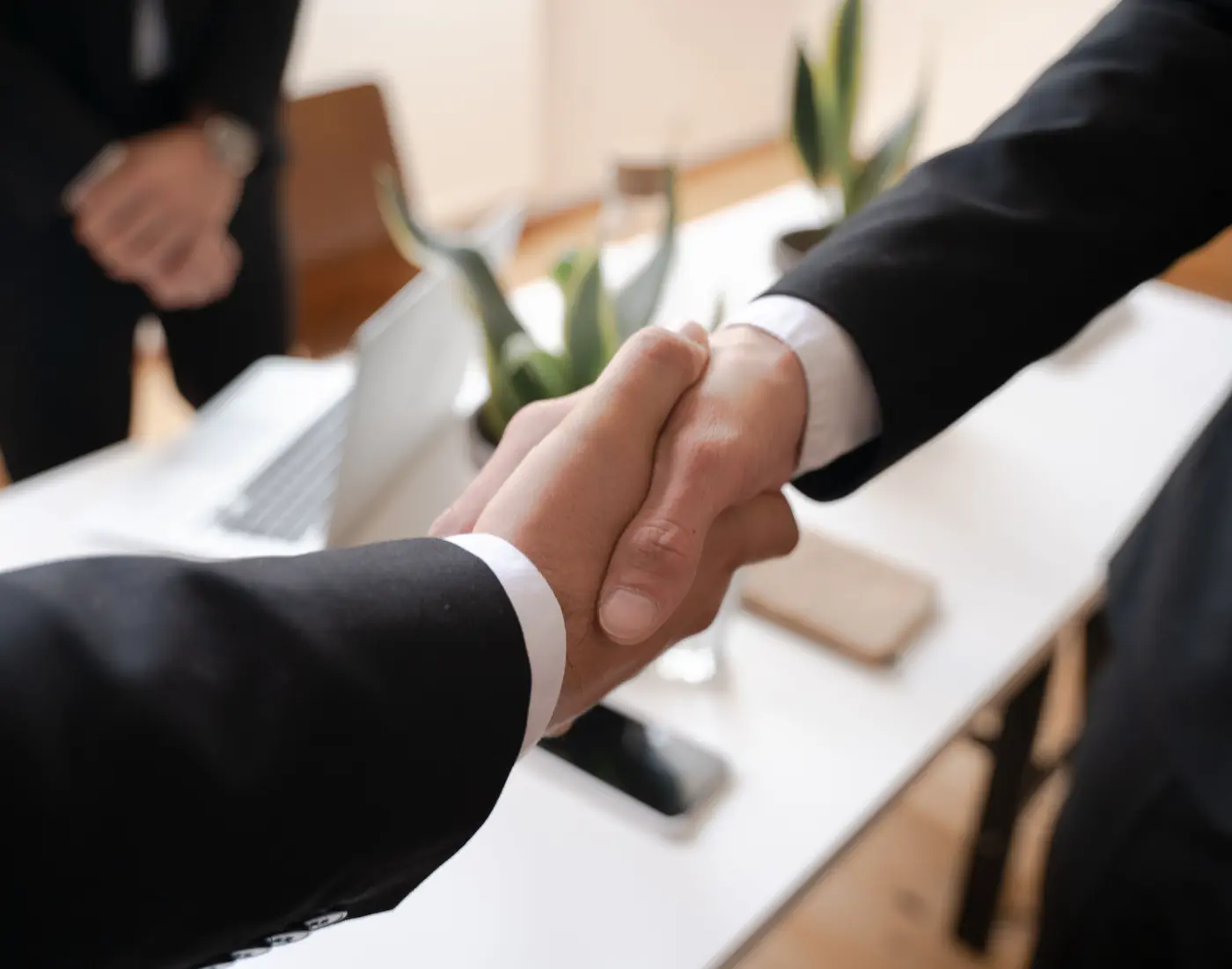 Two business professionals shaking hands in an office setting.