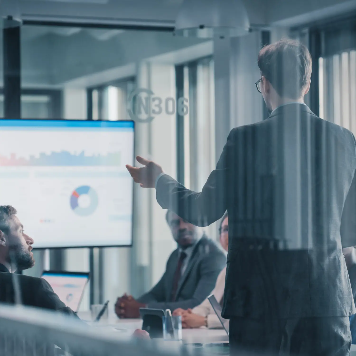 A meeting in progress with a sales dashboard displayed on the background screen.