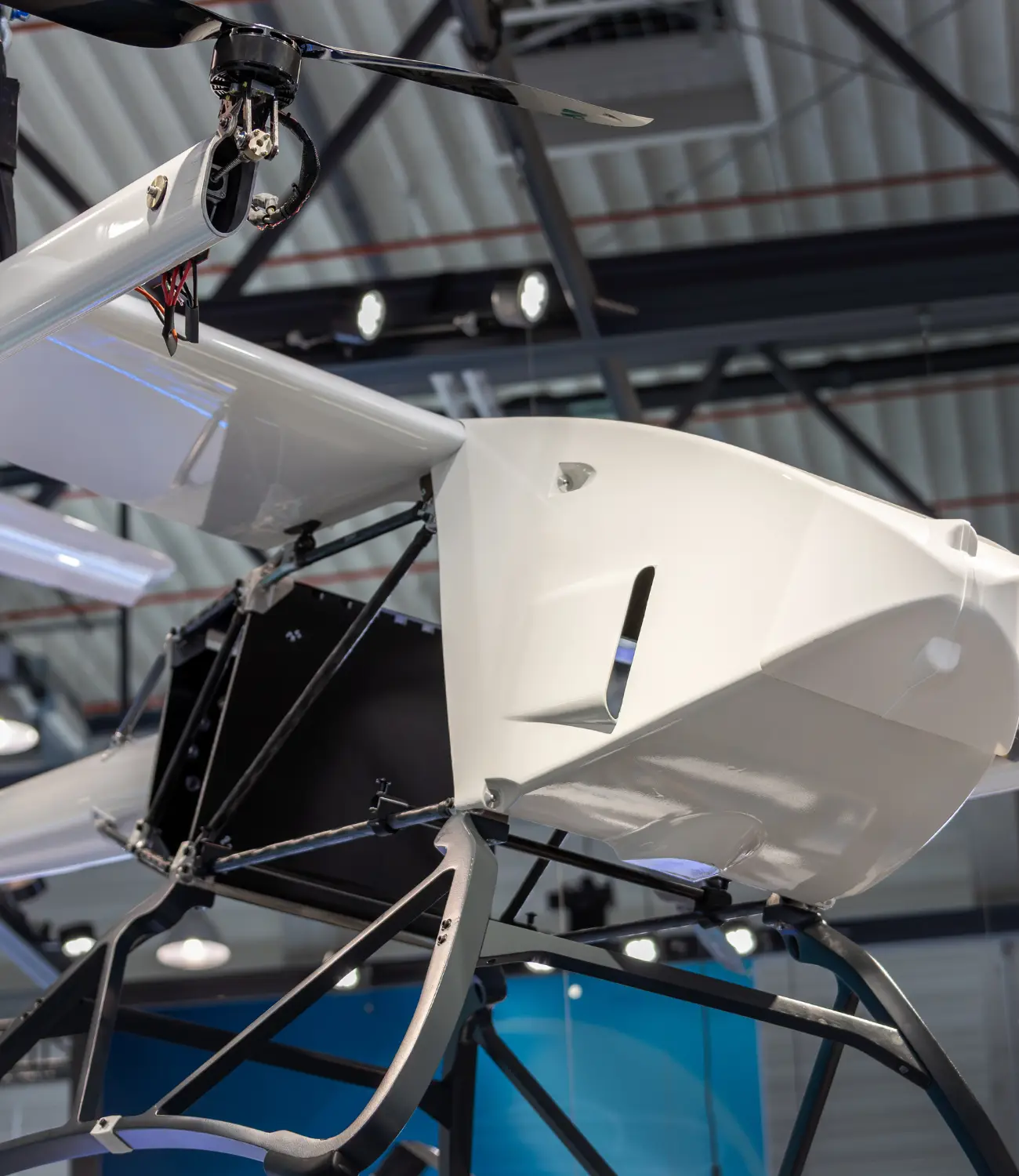 Valkoinen, suuri teollinen eVTOL-rahtidrooni ripustettuna hallin kattoon ilmailualan messuilla.
